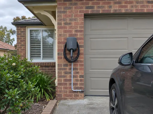 EV charger mounted on a brick exterior wall beside a garage door in a suburban house in Toronto